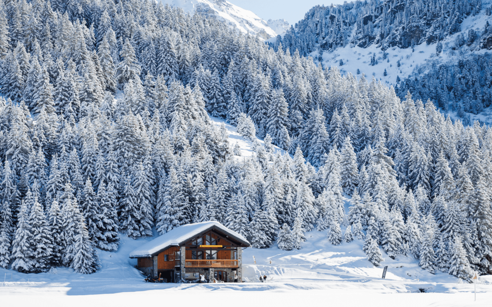 Surface gelée d'un lac d'altitude autour de Méribel en plein hiver entouré de sapins enneigés