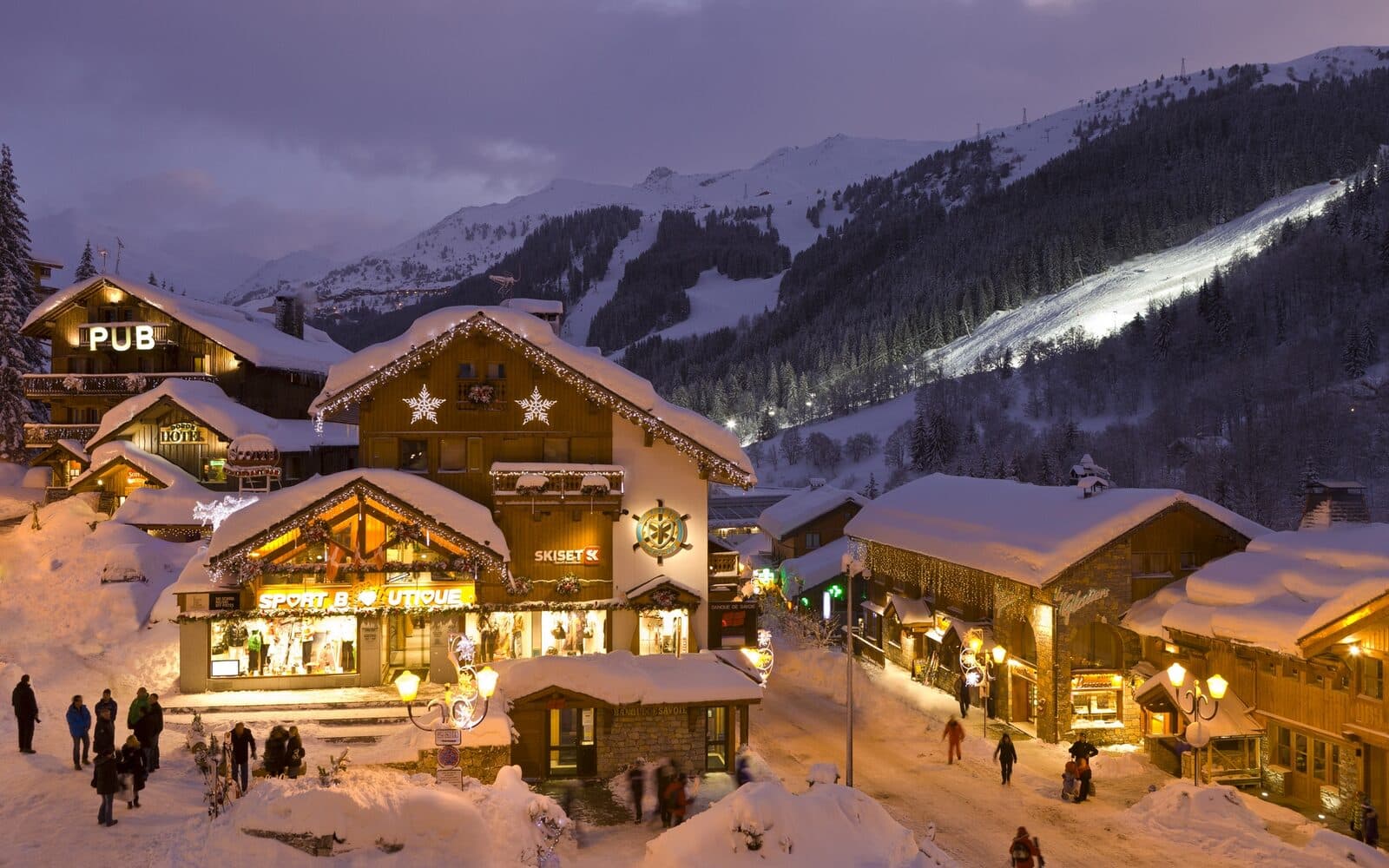 Façade en bois et pierre d'un chalet-hôtel à Méribel Centre sous la neige
