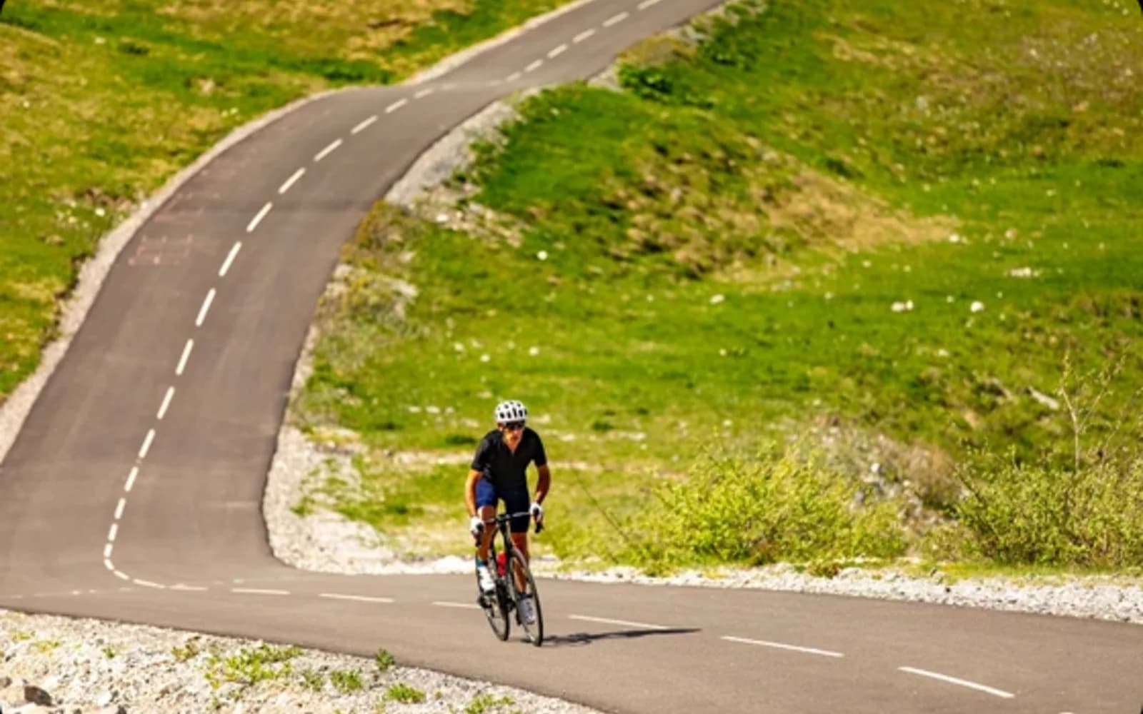 Cycliste sur la route du col de la Loze en été avec panorama sur les Alpes savoyardes